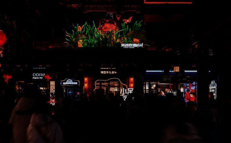 游客手持地图寻找花灯点位,背景是灯火辉煌的豫园夜景