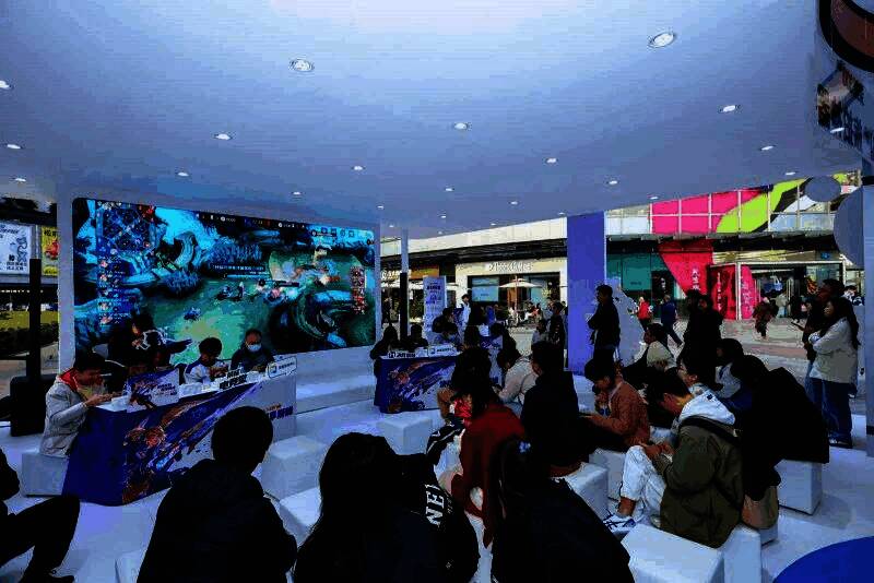 《决胜巅峰》赛事现场观众热情欢呼,背景大屏显示荣耀GT系列手机宣传画面