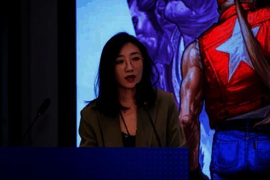 张旭在台上介绍石景山区产业布局，背景为区域发展规划图与游戏产业园区实景