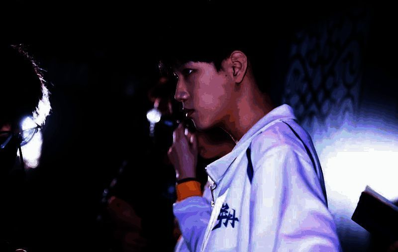 TE_YangY专注比赛中的特写镜头，神情认真，手握设备，背景是IVL赛事现场灯光闪烁