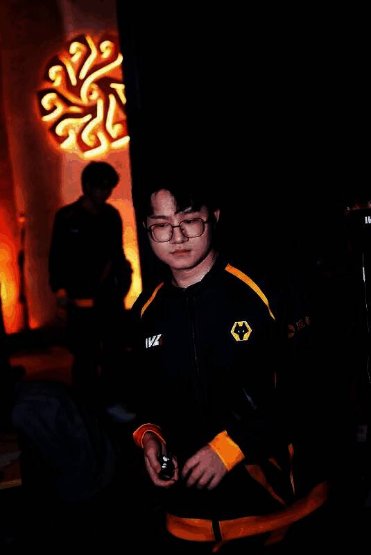 Wolves_Jelly与队友在赛后庆祝胜利，五人并肩站立，高举队旗，现场观众挥舞应援灯海