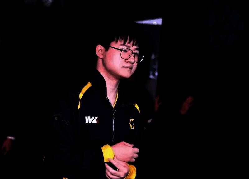 Wolves_Jelly专注比赛中的特写镜头，神情冷静，手握鼠标与键盘，背景为战队LOGO与赛场灯光