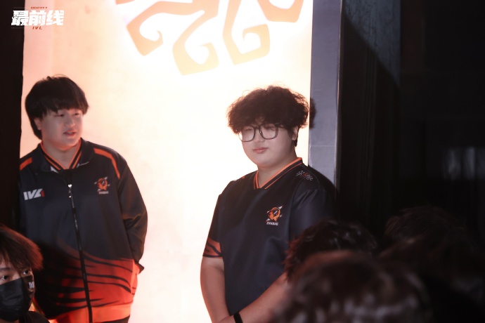 FPX.ZQ战队集体训练场景,Alpaca(左二)正与队友围看战术屏幕,手指指向画面中的监管者走位路径,神情投入